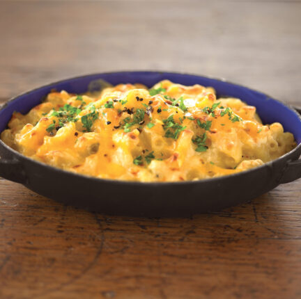 Small cast iron dish with Mac and cheese on a wooden shelf