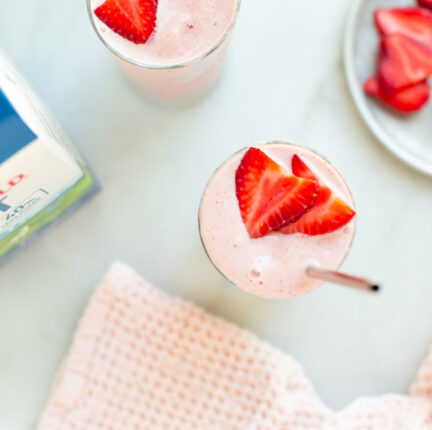 Two strawberry banana smoothies with a bottle of Darigold FIT milk