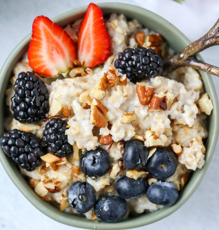 A bowl of oatmeal with blueberries, blackberries, strawberries and nuts