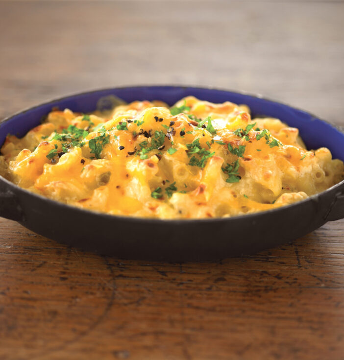 Small cast iron dish with Mac and cheese on a wooden shelf