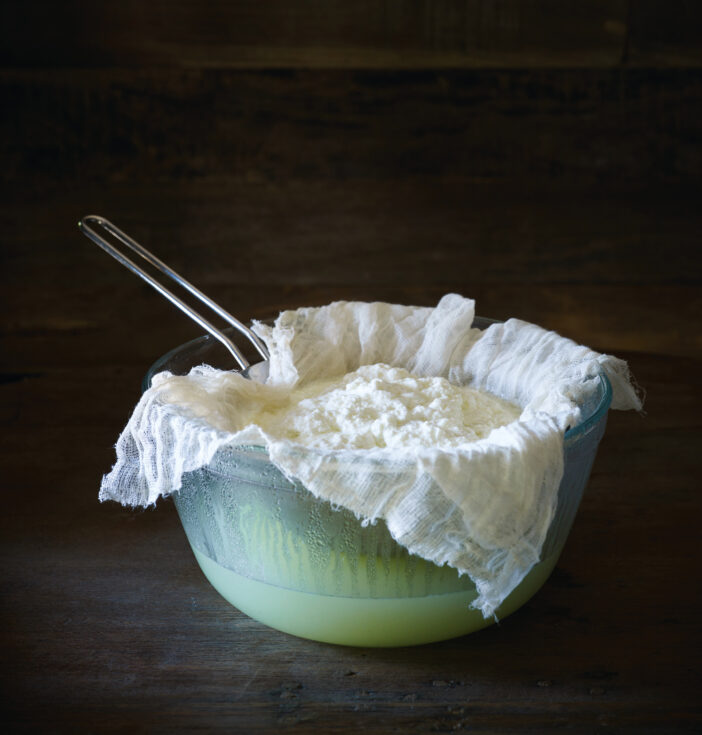 Making ricotta cheese on a dark wooden surface