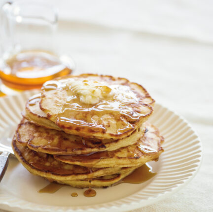 Syrup covered pancakes on a white plate