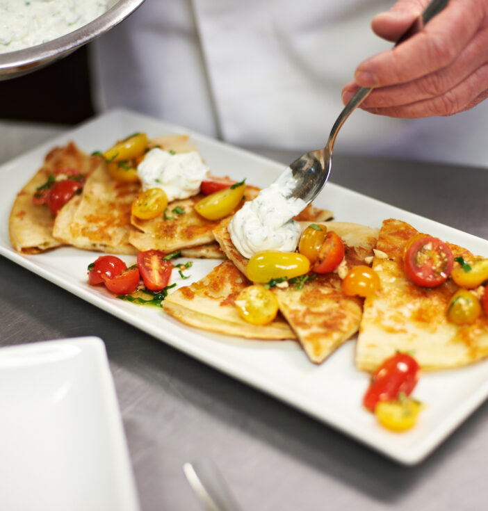 Quesadilla served on a long square plate with cottage cheese and tomatoes