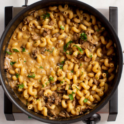A skillet of cheesy pasta on a single burner