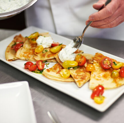 Quesadilla served on a long square plate with cottage cheese and tomatoes